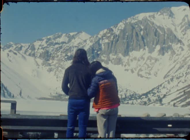 A couple gaze at snowy mountains in an old archive film