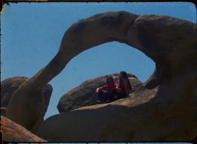A man and woman sitting in a rock formation hold hands
