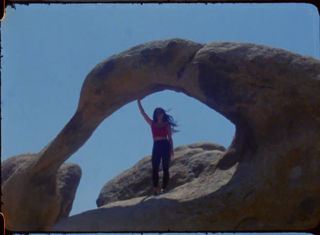Young girl on vacation posing in archway of rack formation daytime her hair is blowing with the breeze