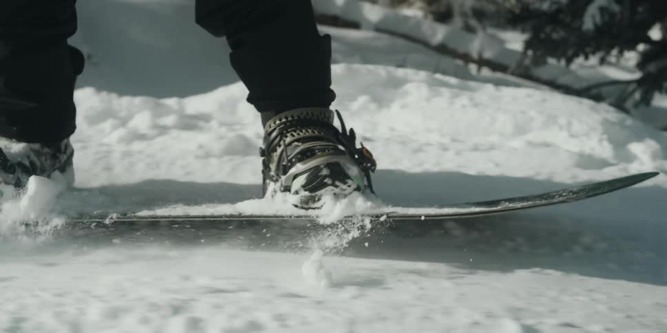 A person snowboarding down the ski run in the mountains during the day heel edge toe edge
