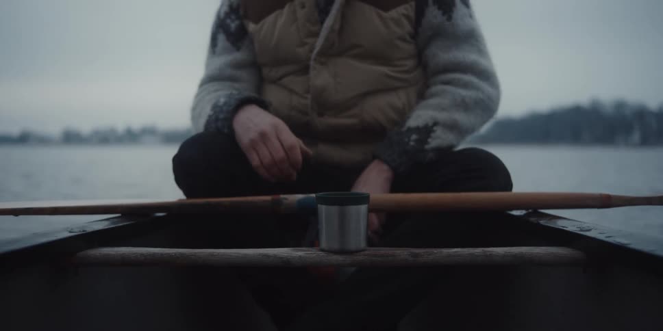 A man is drinking from a cup and sitting on a boat
