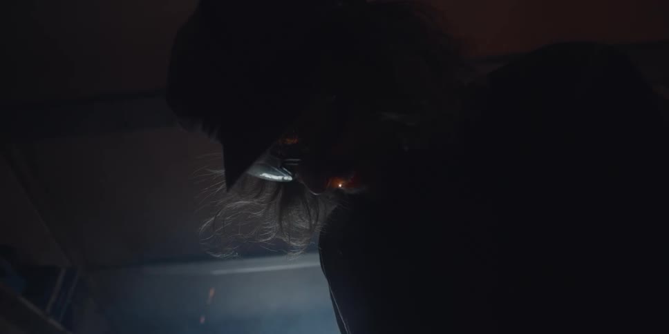A person wearing face protection and sparks flying from below