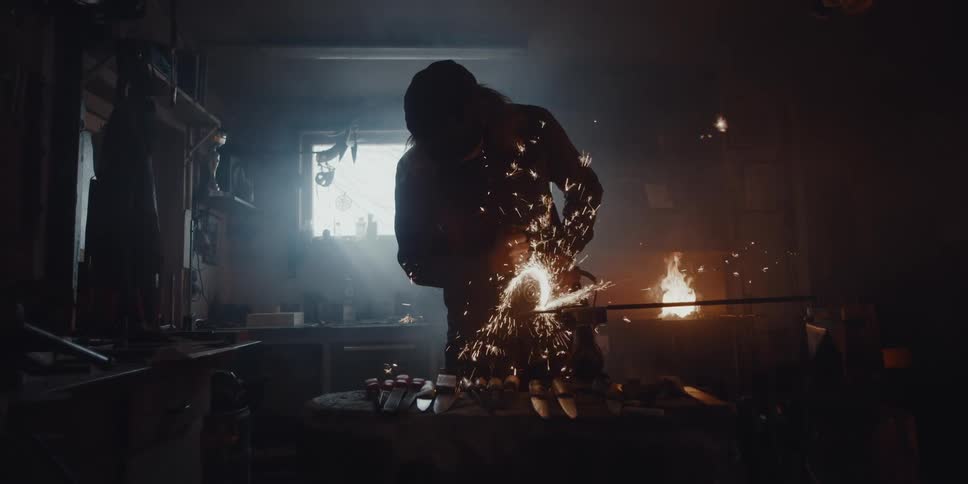 The silhouette of a person is seen as they create sparks using a metal grinder