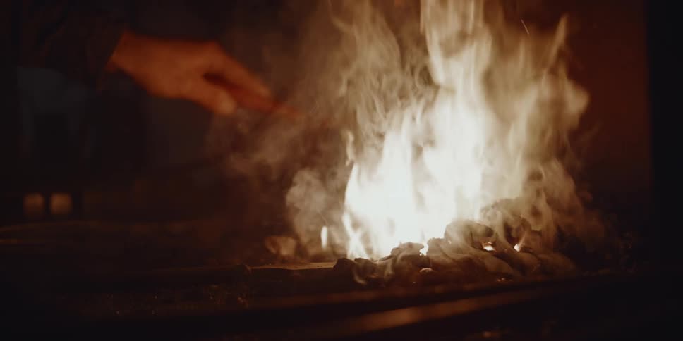 Blacksmith in workshop quenching the forge fire with brush and water