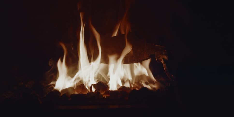 Flames from a burning fire are used to cook a piece of food in the darkness