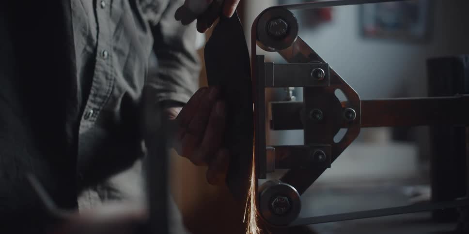 A man is sharpening a tool with machinery