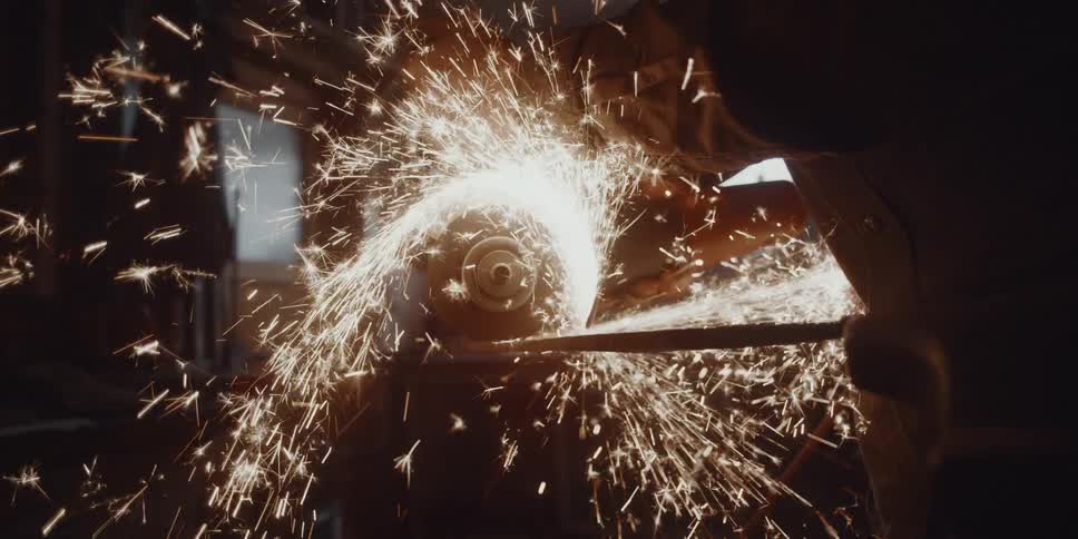 Sparks fly as a man uses a table saw on metal