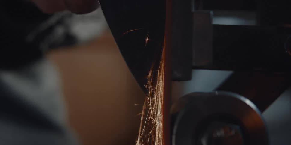 A person sharpens a piece of metal using a grinding tool