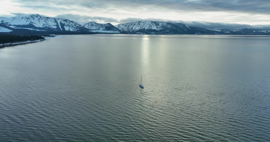 An aerial view of a sailboat approaching a snowy coast