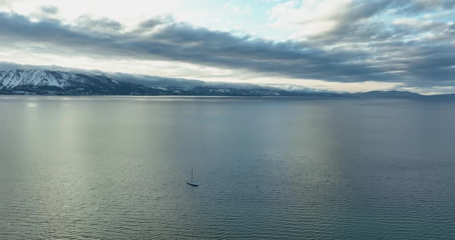 Aerial view of boat sailing on ocean near the snowy mountains