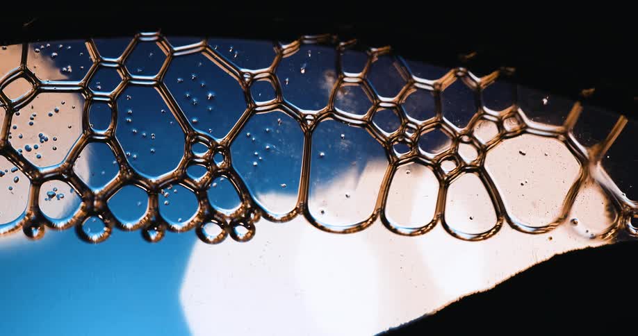 The view moves peeking through dark cover and light shines in a blue background as bubbles move across the surface