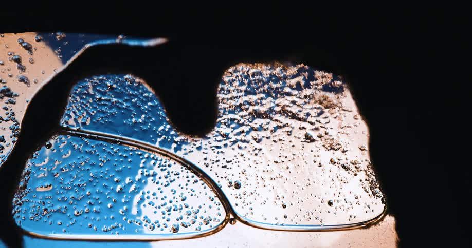 Foam with large and small bubbles allows glimpses of light spots through glass