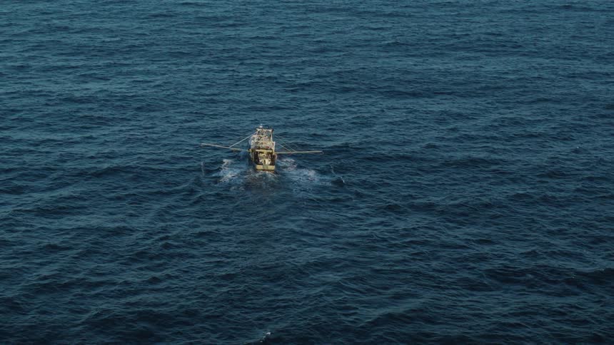 Aerial view of a boat sailing through the ocean sea