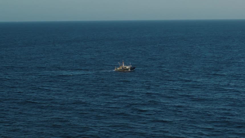 A ship is sailing across the deep blue water as it ripples and waves