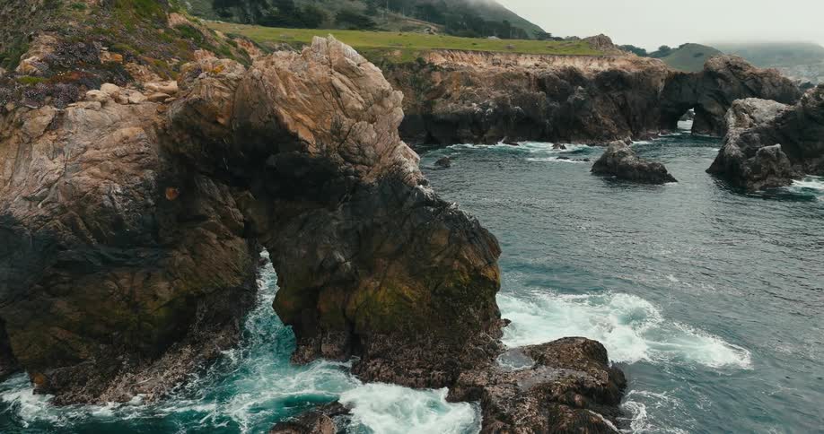 Deep blue ocean waves crashing under rock arch