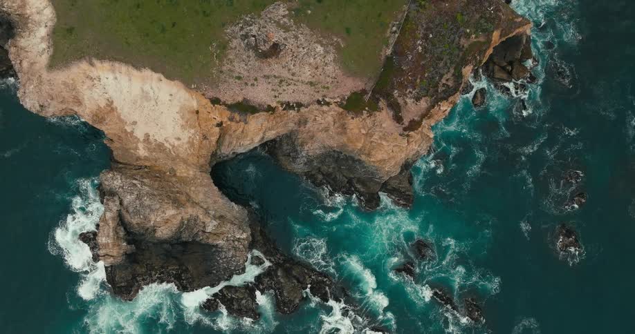 Aerial view of waves crashing on rocks along the shore