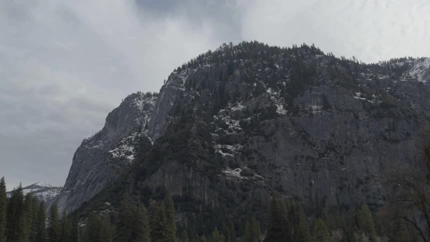 Clouds hover over a steep and rocky mountain ridge