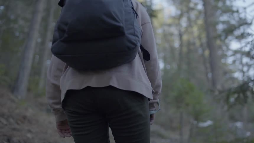 A woman walking a dog hikes along a path