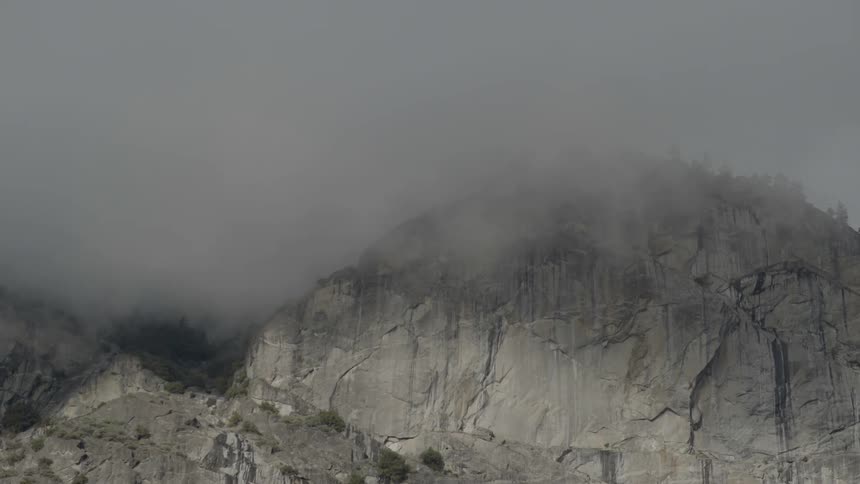 Fog or low clouds move over a tall cliff face