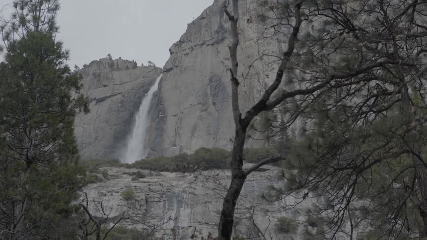 A waterfall cascading down a mountain behind some trees