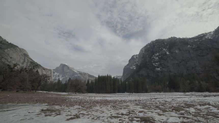 Mountains and trees lightly covered in snow on a cloudy day