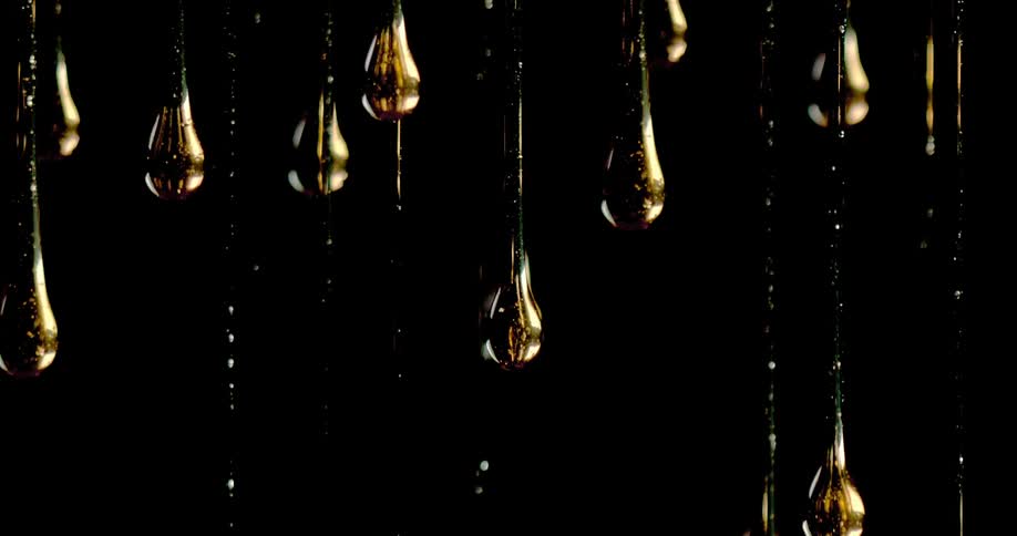 Gold droplets falling in front of a black background