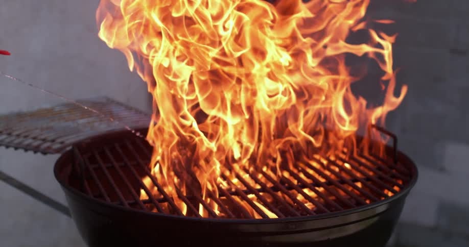 Lighter fluid is squirted onto burning coals in a charcoal grill