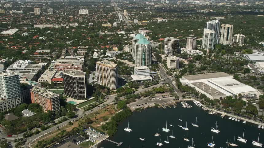 Flying above beautiful Coconut Groves office buildings with a stunning view of the Miami coastline in sunny Florida