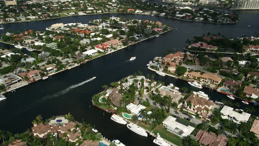 Aerial footage of upscale residential neighborhoods along canals and water bodies in Fort Lauderdale Florida with boats sailing by