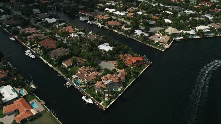 The aerial footage shows a canal in Fort Lauderdale Florida with mansions along its banks as the camera tilts down towards them