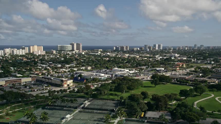 An aerial flyover of Pompano Community Park and approach to condos along the shoreline of Pompano Beach Florida on a partly cloudy day