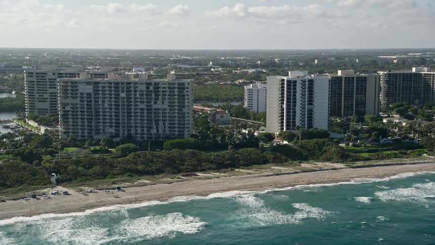 Aerial footage flying over apartment buildings on the beach in Boca Raton Florida during a partly cloudy day