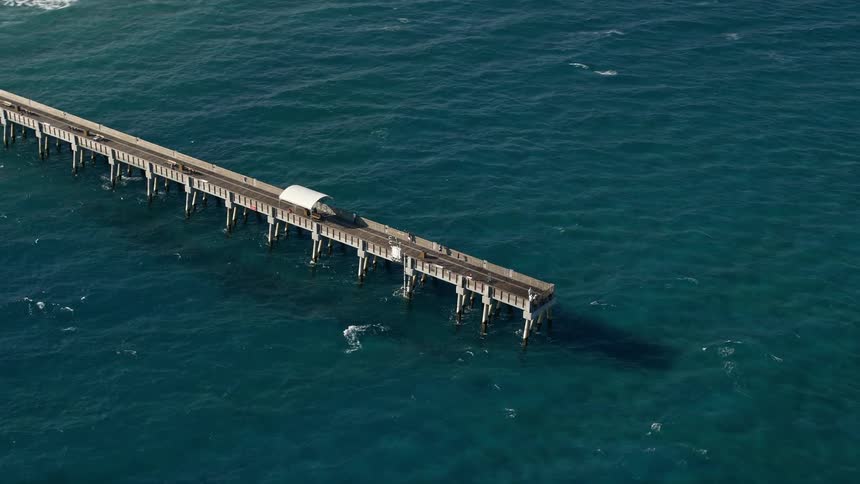 A beautiful aerial shot of Lake Worth Pier Palm Beach Florida on a partly cloudy day during summer