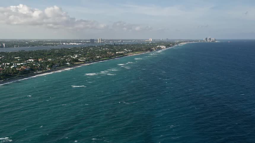 Aerial footage of Palm Beach Floridas suburban coastline with a view of the city in the distance capturing the beauty of the coastal community