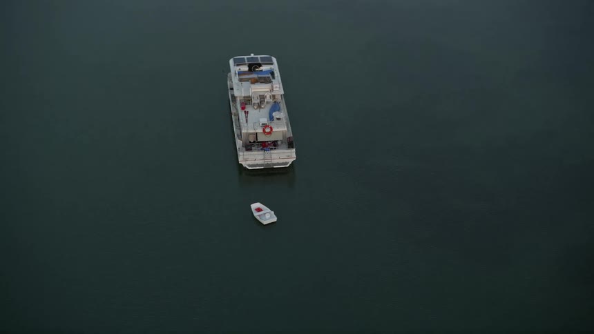 An aerial view of a houseboat orbiting near the shore at sunset in Key Largo Florida