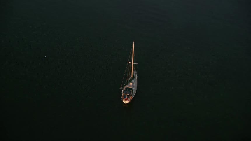 A sailboat approaches the shore during a beautiful sunset in Key Largo Florida in this aerial footage