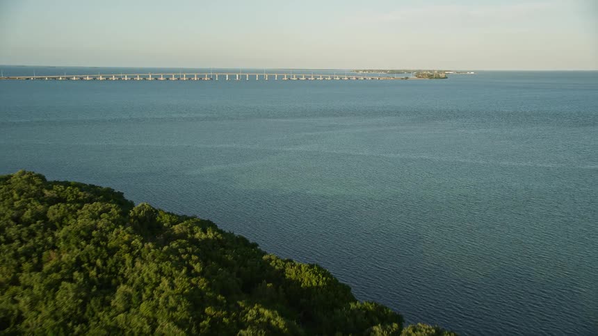 A sweeping aerial view of the Overseas Highway bridge connecting Floridas islands over a backdrop of mangroves and a stunning sunset