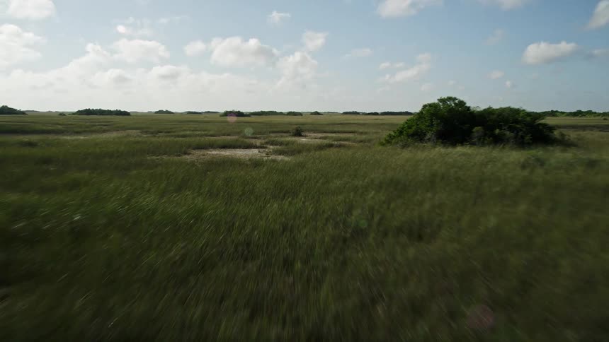 Flying over marshland and wetlands in Floridas Everglades National Park during a partly cloudy day-time view