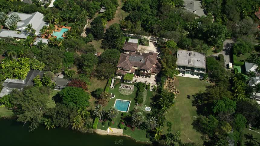 Approaching a luxurious mansion the camera tilts down to reveal the sprawling property nestled in a residential neighborhood in Coral Gables Florida