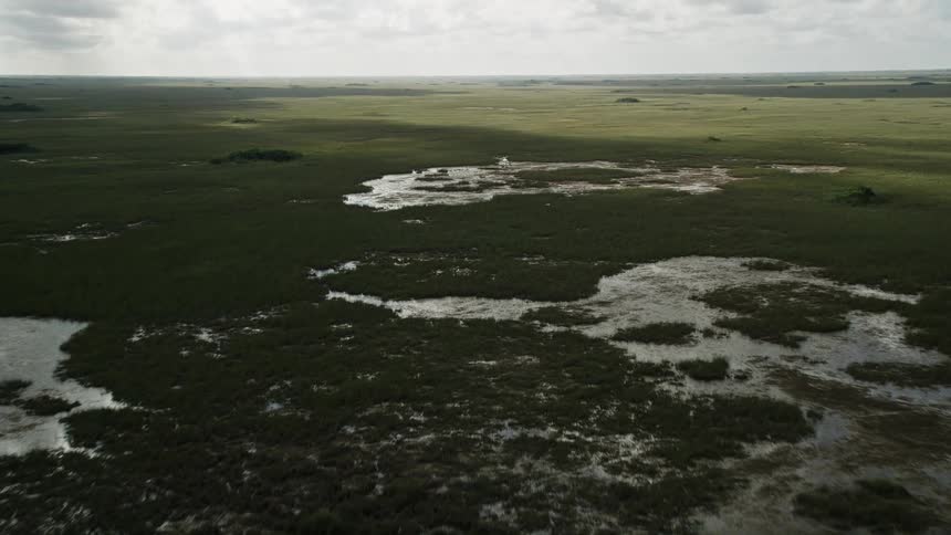 Flying over the Florida Everglades marshland on a partly cloudy day
