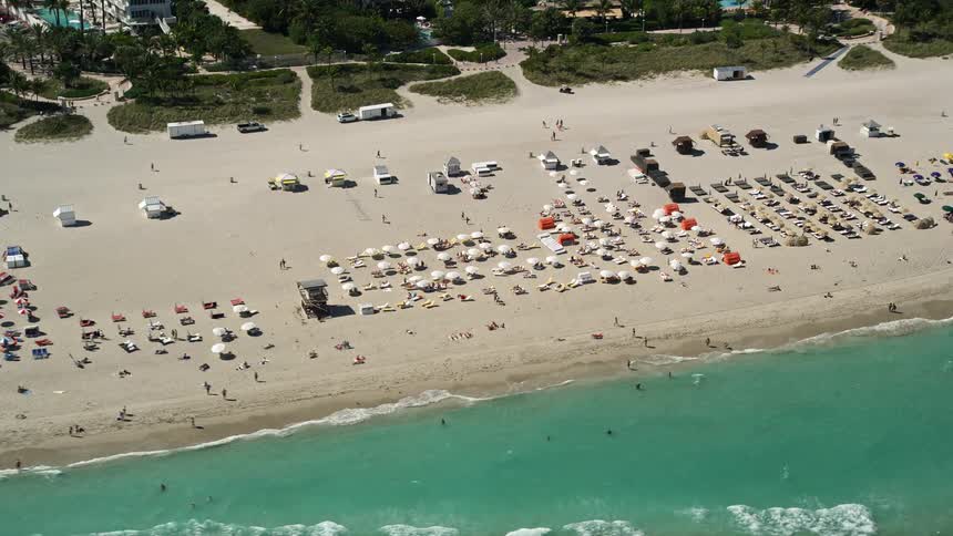 Aerial footage of buzzing South Beach Miami exhibiting sunbathers enjoying the sunshine and the seashores