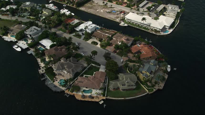 Aerial view of luxurious waterfront mansions along canals in Fort Lauderdale Florida tilting down to showcase the upscale homes