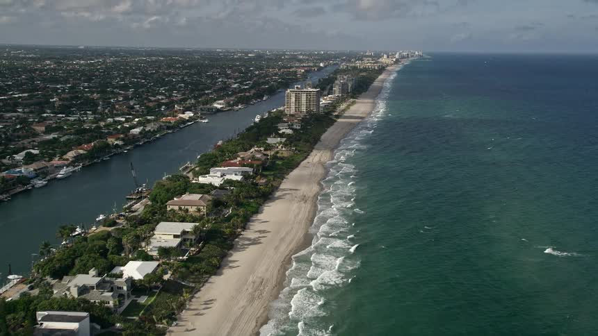 Fly over breathtaking oceanfront properties and beach houses revealing the stunning coastline and Hillsboro Beach in South Florida