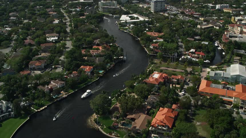 Aerial view of New River flowing through residential mansions before revealing the downtown area of Fort Lauderdale Florida with towering buildings