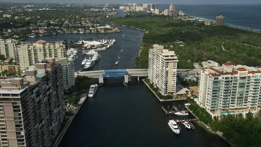 An aerial shot follows a canal past apartments the East Sunrise Boulevard bridge and the shoreline of Fort Lauderdale Florida