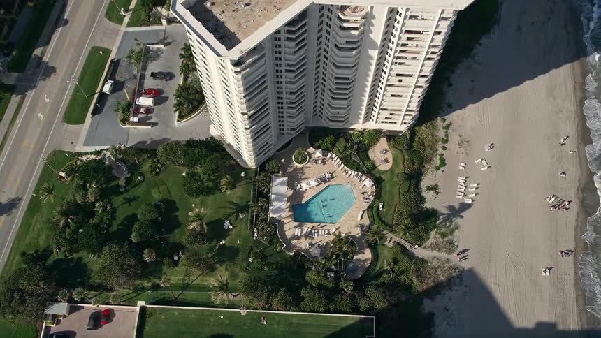 Aerial view of a coastal condominium complex and pool area surrounded by lush greenery in Boca Raton Florida