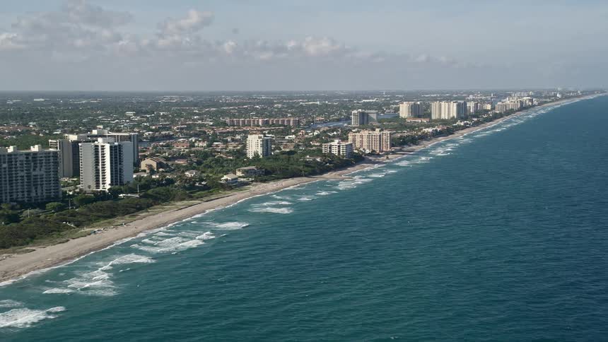 Aerial footage of the coastline along Boca Raton Florida capturing shoreline residences and nature scenes with partly cloudy skies