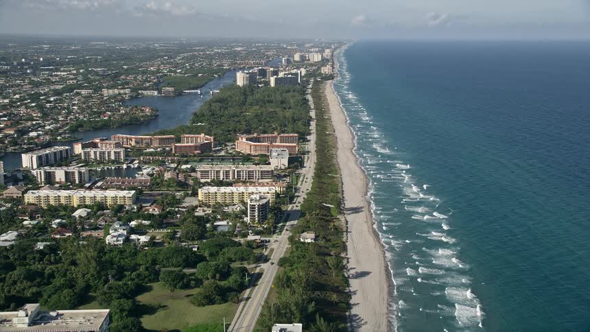 An aerial tour of a condo complex situated on North Ocean Boulevard and the coastline in Boca Raton Florida during the summer season