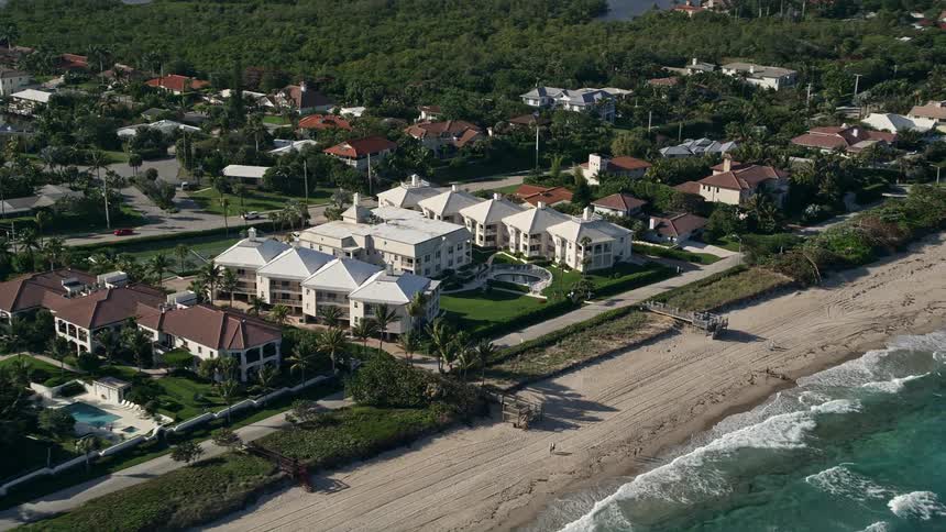 Aerial footage of a condominium complex by the shore in Ocean Ridge Florida with beachfront property and partly cloudy skies