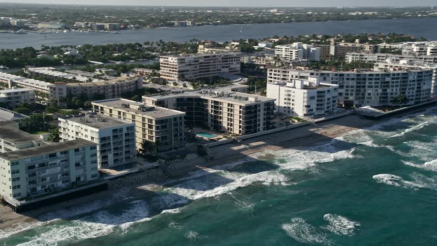 Aerial view of an apartment building along the beachfront of Palm Beach Florida on a partly cloudy day during summer